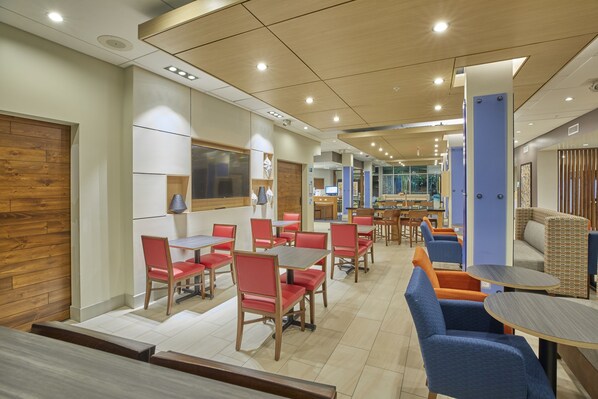 A modern dining area with wooden walls, red and blue chairs, and a central table. - Holiday Inn Express & Suites Hermiston Downtown by IHG (Hermiston)