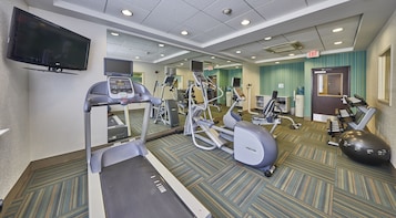 A hotel fitness center with treadmills, elliptical machines, and free weights.