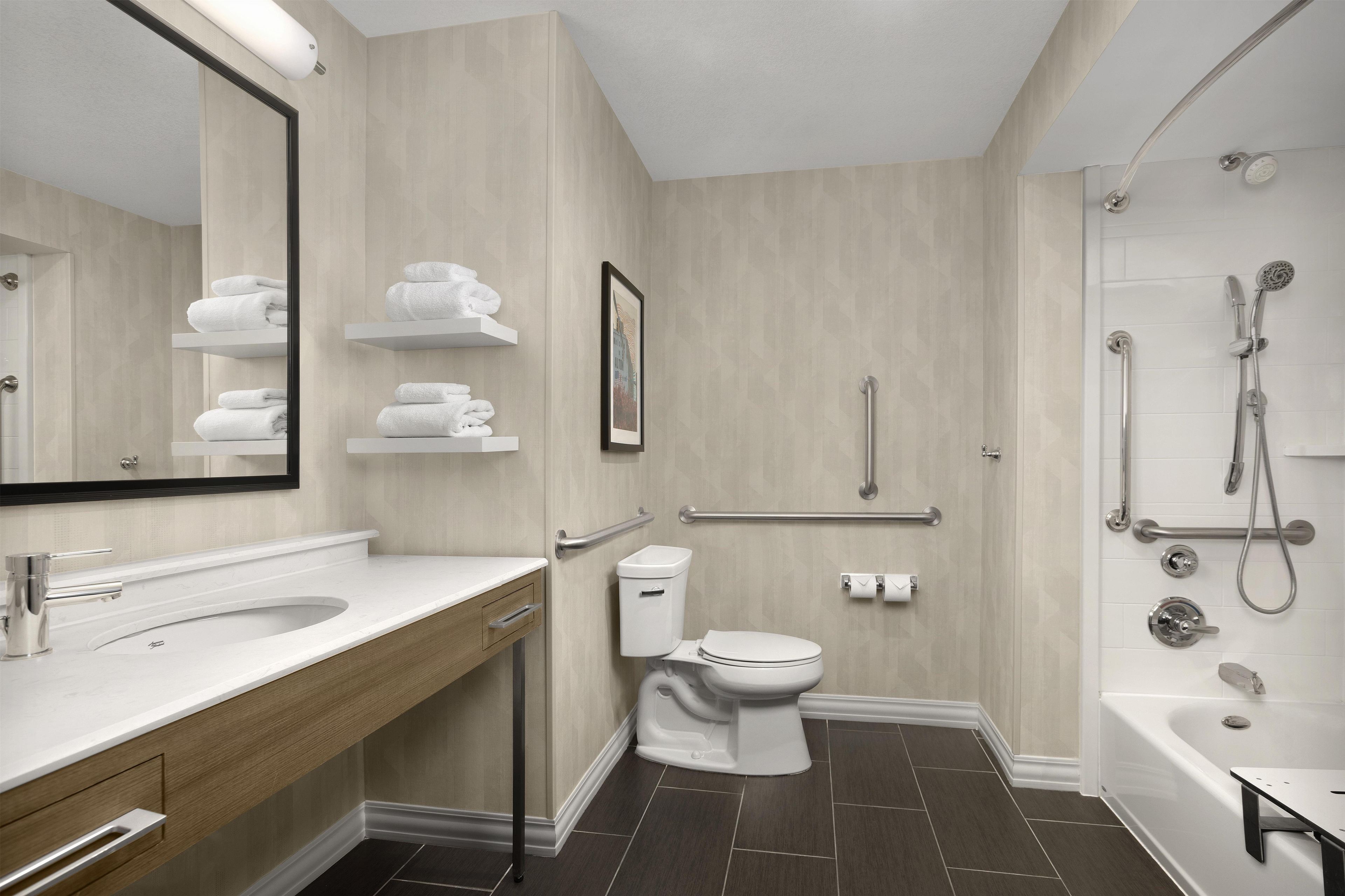 A modern bathroom with a large mirror, a sink, a toilet, and a shower area.