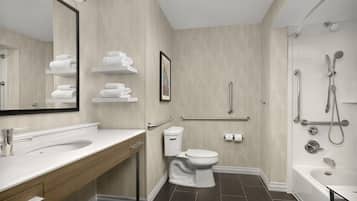 A modern bathroom with a large mirror, a sink, a toilet, and a shower area.