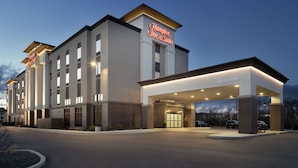 Modernilla designilla varustettu Hampton Inn & Suites -hotelli, jossa on suuri sisäänkäynti ja hyvin valaistu julkisivu.