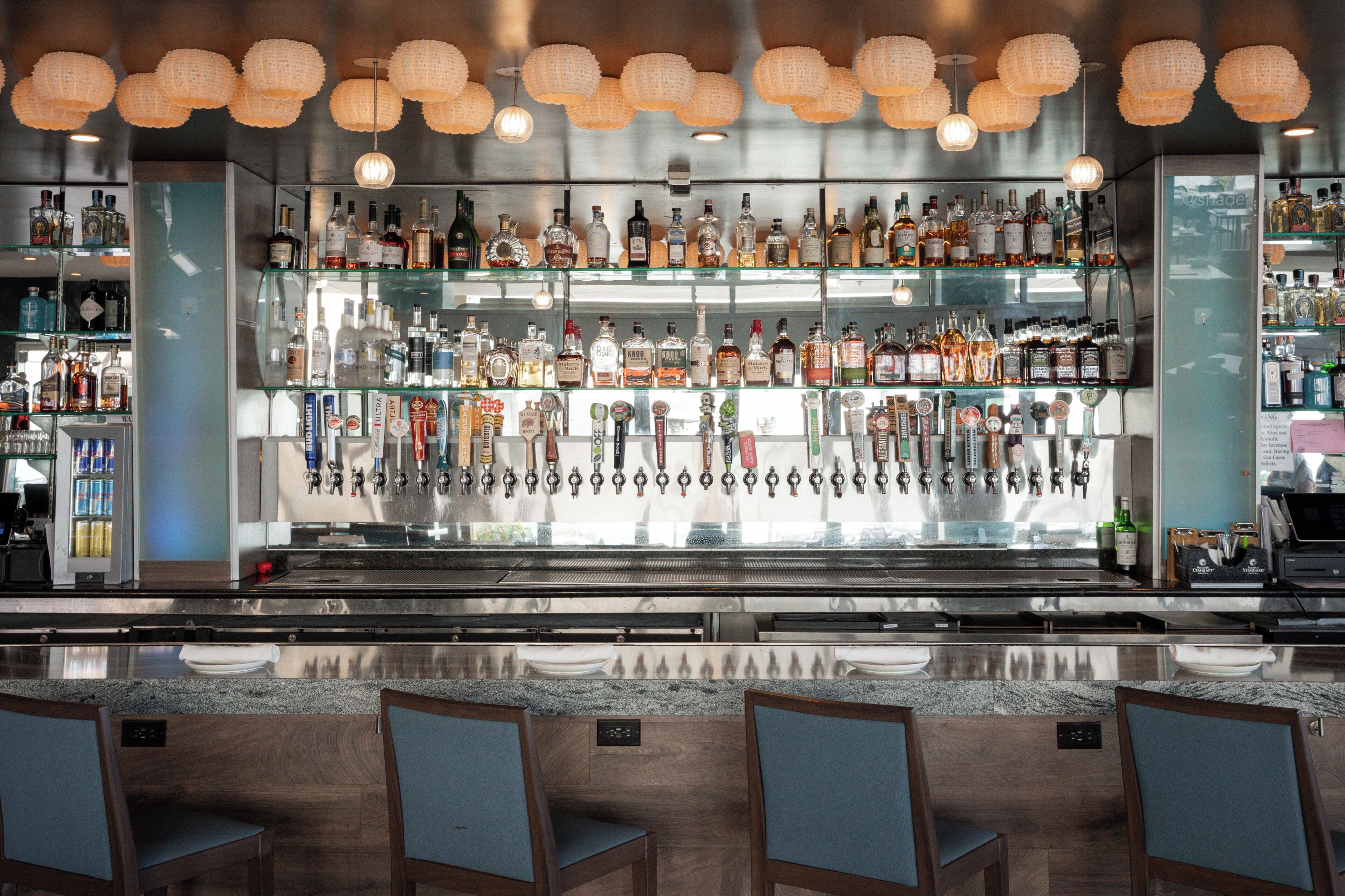 Eine Bar mit mehreren Regalen voller Spirituosenflaschen, einer Theke und Sitzgelegenheiten.