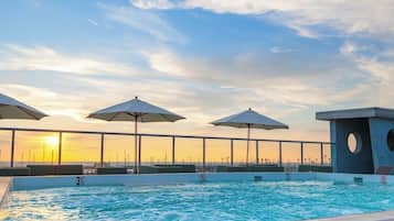 Enjoy a refreshing swim with a stunning ocean view from the rooftop pool, surrounded by shaded areas and a secure railing.