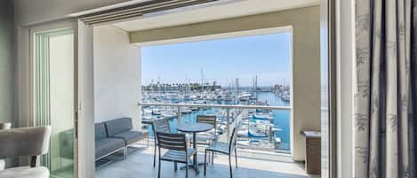 A balcony with a view of a marina, a seating area with chairs and a table, and a door leading to another room.