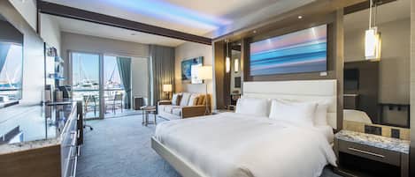 Habitación de hotel moderna con una cama grande, un escritorio y vistas a barcos a través de las ventanas.