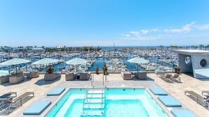 A rooftop pool area with multiple lounge chairs and umbrellas, overlooking a marina with numerous boats. - Shade Hotel Redondo Beach (Redondo Beach)