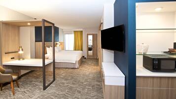 A hotel room with a bed, desk, chair, TV, and microwave.