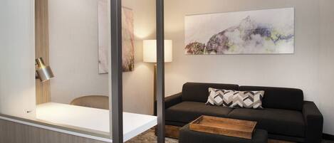 Et moderne hotelværelse med en sofa, skammel og et billede på væggen.