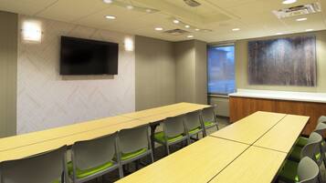 Uma sala de conferências com uma mesa comprida, cadeiras, uma TV de tela plana e uma tela de projeção.