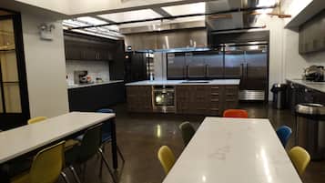 Een moderne keuken met roestvrijstalen apparatuur, een marmeren aanrechtblad en een zithoek met gele stoelen.