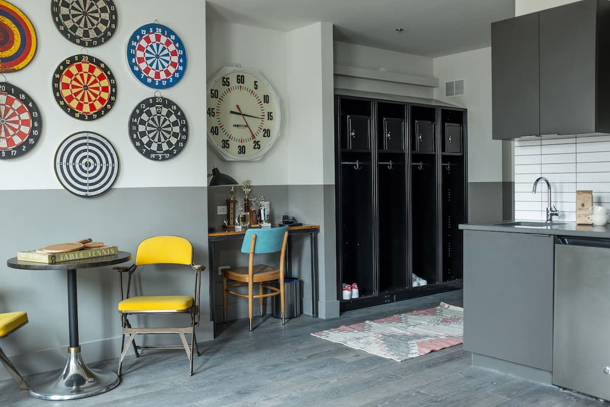 A modern kitchen with a dartboard, a clock, and a dining area with a table and chairs.