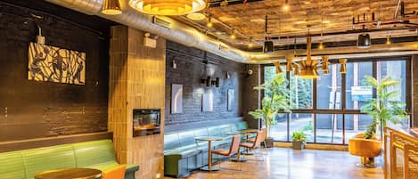 A modern interior with exposed ductwork, a bar area, seating, and large windows.