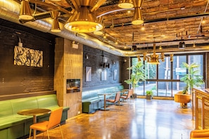 A modern interior with exposed ductwork, a bar area, seating, and large windows. - The Chicago Hotel Collection River North (Chicago)