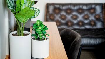 A room with a wooden table, two potted plants, a couch, and a painting on the wall.