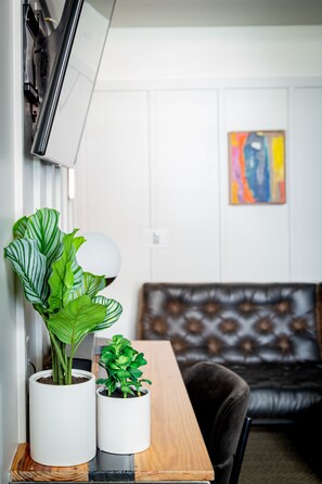 A room with a wooden table, two potted plants, a couch, and a painting on the wall. - The Chicago Hotel Collection River North (Chicago)