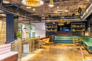 A modern interior with exposed ductwork, a bar area, seating, and a staircase. - The Chicago Hotel Collection River North (Chicago)