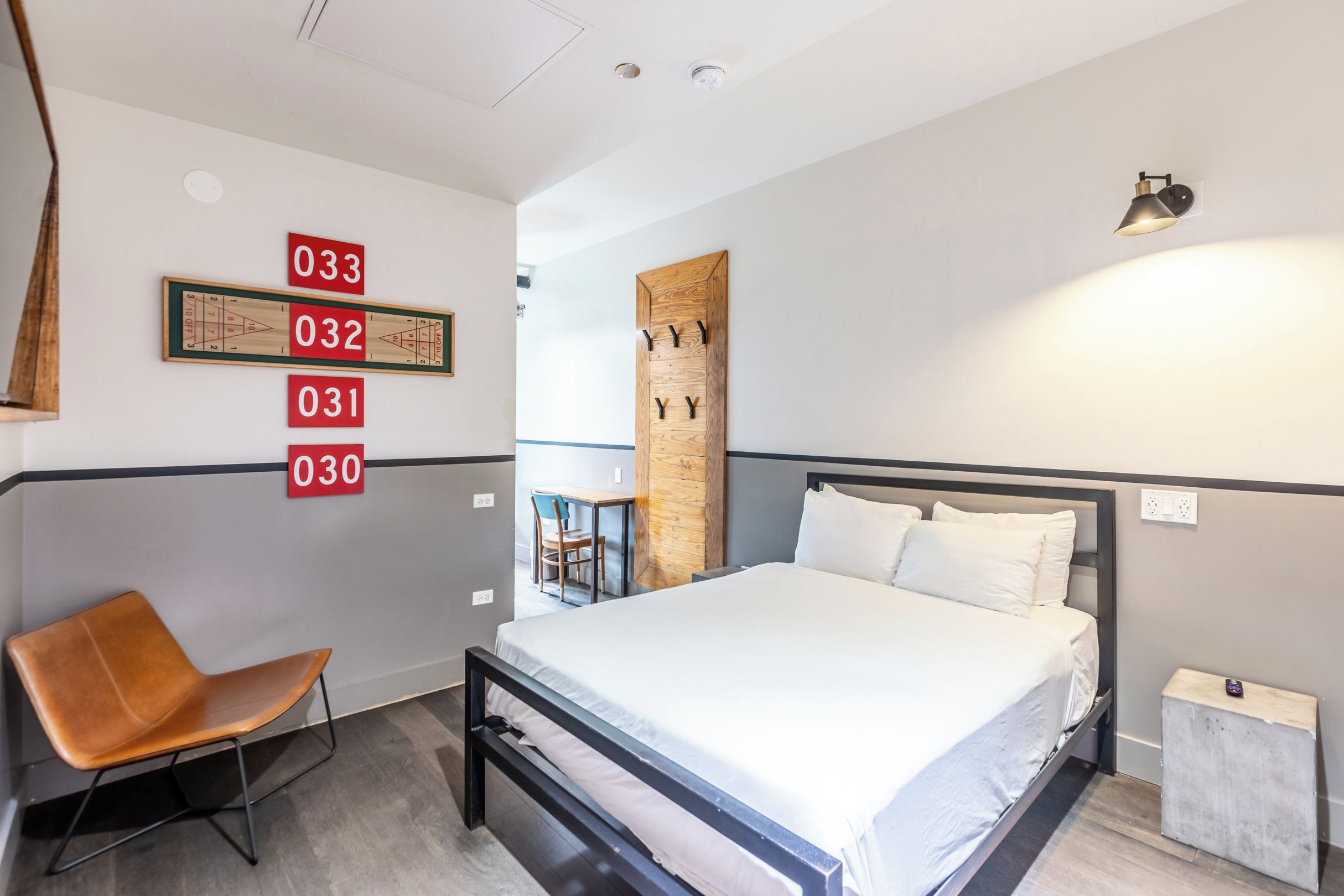 Une chambre d’hôtel équipée d’un lit, d’une chaise, d’un bureau et d’un panneau indicateur fixé au mur.