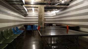A room with striped walls, a ping pong table, and several chairs.