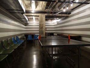 A room with striped walls, a ping pong table, and several chairs. - The Chicago Hotel Collection River North (Chicago)