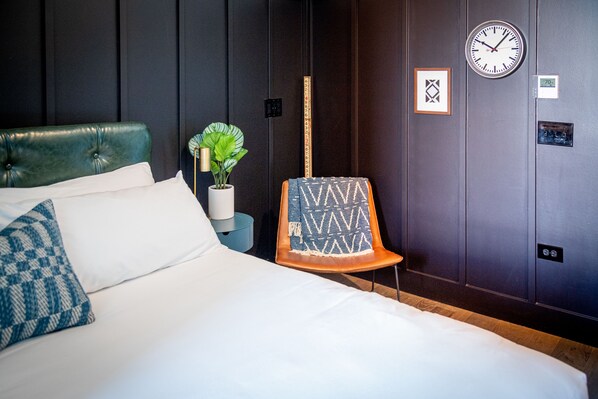 A hotel room with a bed, a chair, a clock, and a plant. - The Chicago Hotel Collection River North (Chicago)