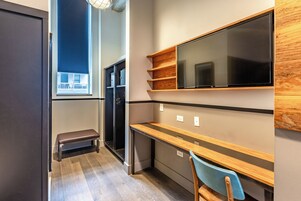 Una cocina moderna con microondas integrado, estanterías de madera, un banco y un ventanal grande.