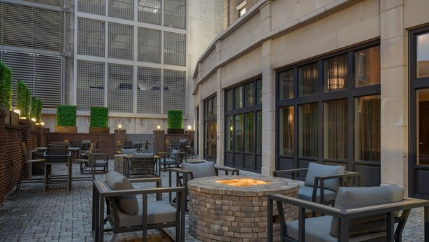 An outdoor patio area with brick flooring, seating arrangements, and a central fire pit. - Fairfield Inn & Suites Savannah Downtown/Historic District (Savannah)