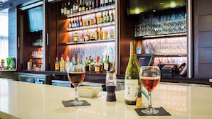 A bar area with shelves of various liquor bottles, a wine bottle, and glasses on the counter. - Fairfield Inn & Suites Savannah Downtown/Historic District (Savannah)