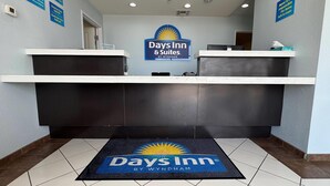 A reception area with a reception desk, a sign for Days Inn & Suites by Wyndham, and a doormat with the hotel's logo. - Days Inn & Suites by Wyndham Colorado City/I-20 (Colorado City)