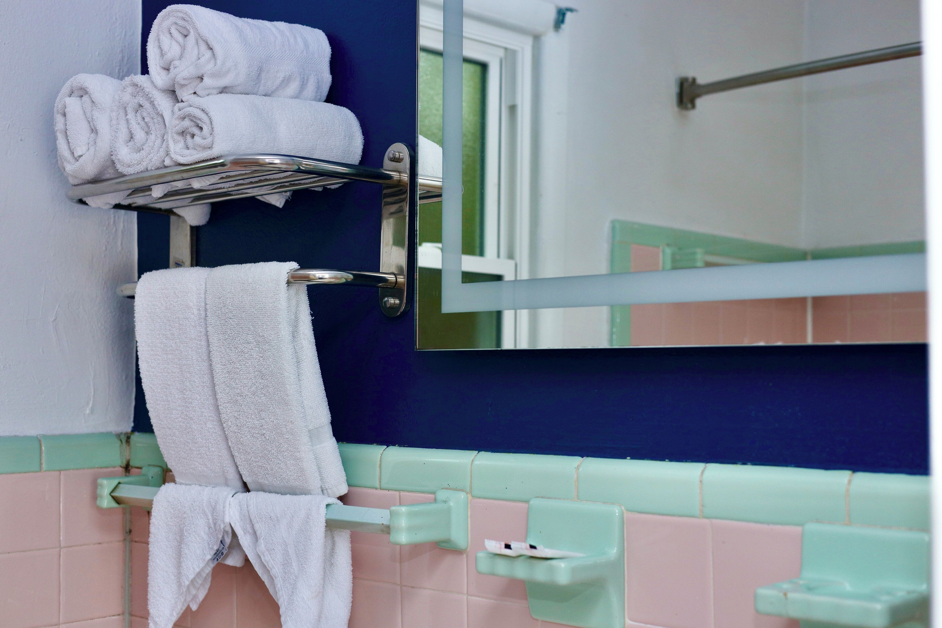 Un baño con un perchero para toallas, un espejo y un jabonera verde.