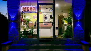 A building entrance with a neon 'OPEN' sign, a reception desk, and a clock. - Twi-Lite Inn (Front Royal)