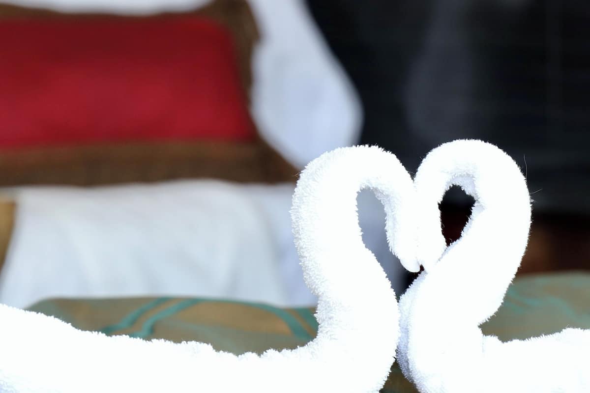 A bed with a heart-shaped towel arrangement.