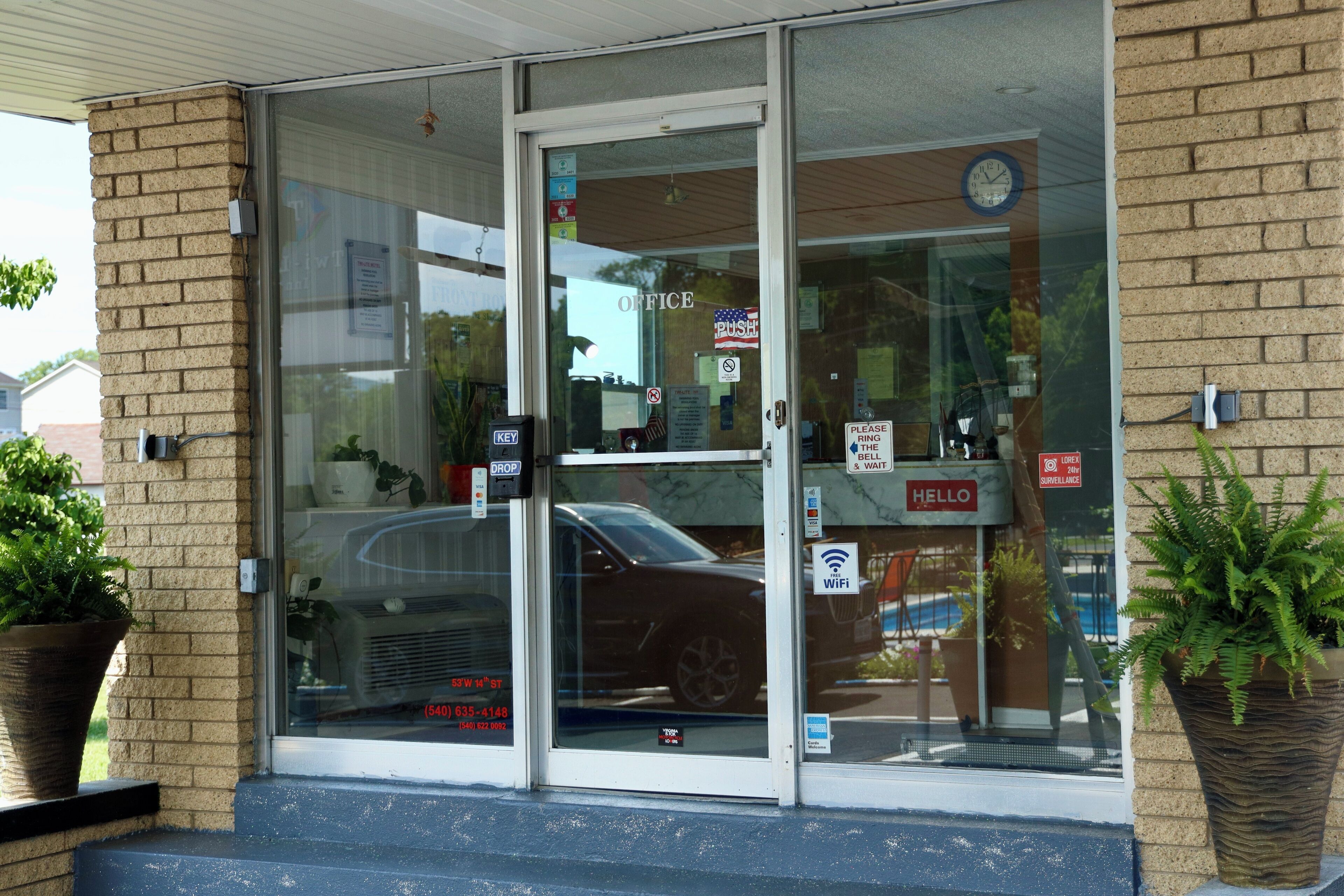 A building entrance with glass doors, a brick wall, and a 'Hello' sign.