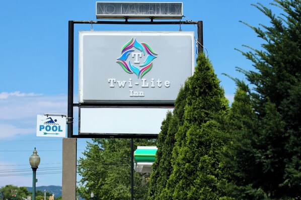 Letrero del TWI-Lite Inn con un cartel que indica la dirección a la piscina.