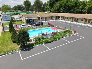 A motel with a swimming pool, outdoor seating, and a gas station in the background. - Twi-Lite Inn (Front Royal)
