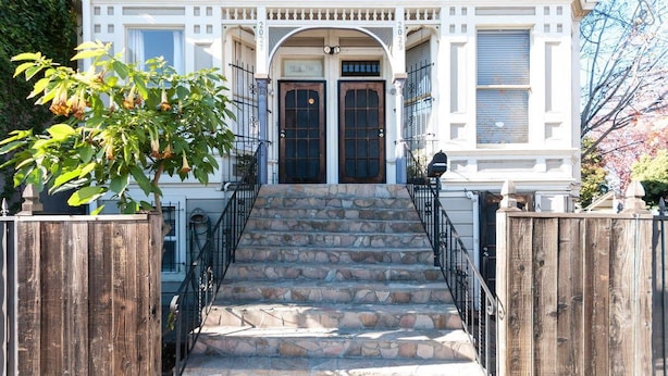 A two-story house with a stone staircase leading to a dark wooden door. - Stunning 1 Bedroom Flat (Oakland)