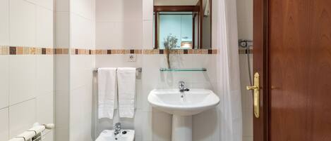 Une salle de bain avec un lavabo blanc, un bidet et un miroir au-dessus du lavabo.