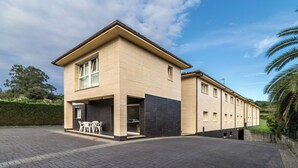 Un bâtiment moderne à deux étages, doté d’un toit plat, de grandes fenêtres et d’une allée pavée.
