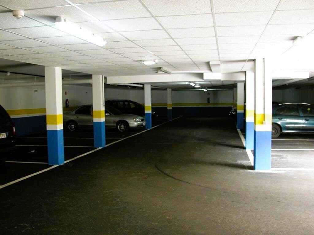 Un parking à plusieurs niveaux, avec des piliers blancs et des rayures bleues et jaunes.