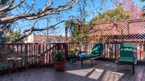 A wooden deck with outdoor furniture, potted plants, and a pergola structure.