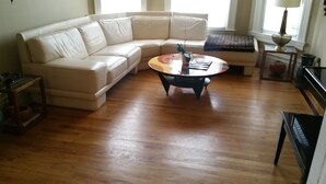 A living room with a beige sectional sofa, a round coffee table, and a wooden floor.