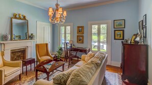 A living room with a fireplace, a chandelier, a sofa, and a desk. - Steele Cottage (Vicksburg)