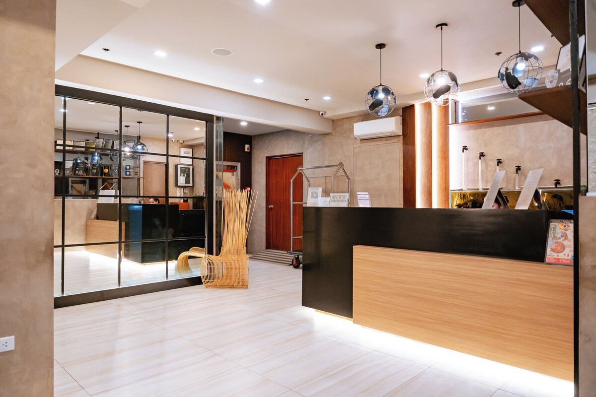 A hotel reception area with a modern design, including a reception desk, a glass partition, and a seating area.