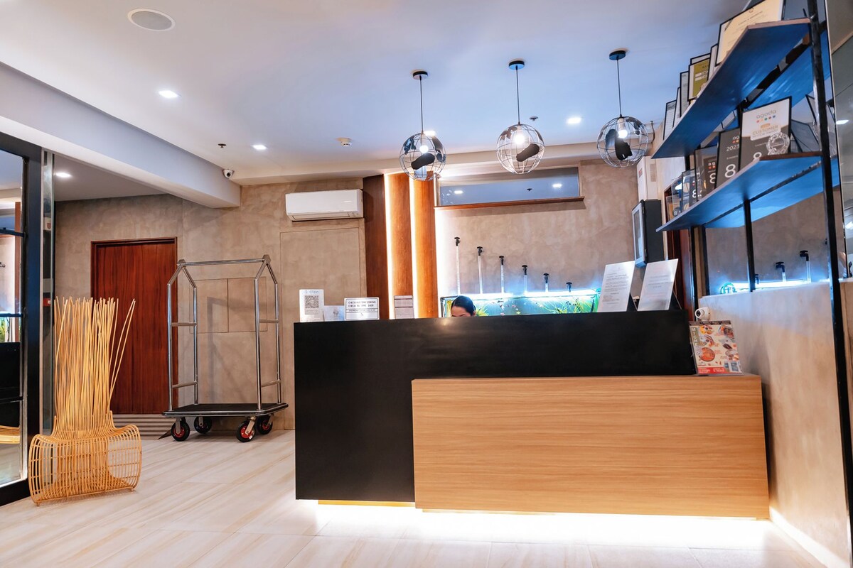 A modern reception area with a black counter, wooden flooring, and pendant lighting.