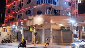 Un hotel con una fachada ondulada distintiva, señalización iluminada y un bistro visible.