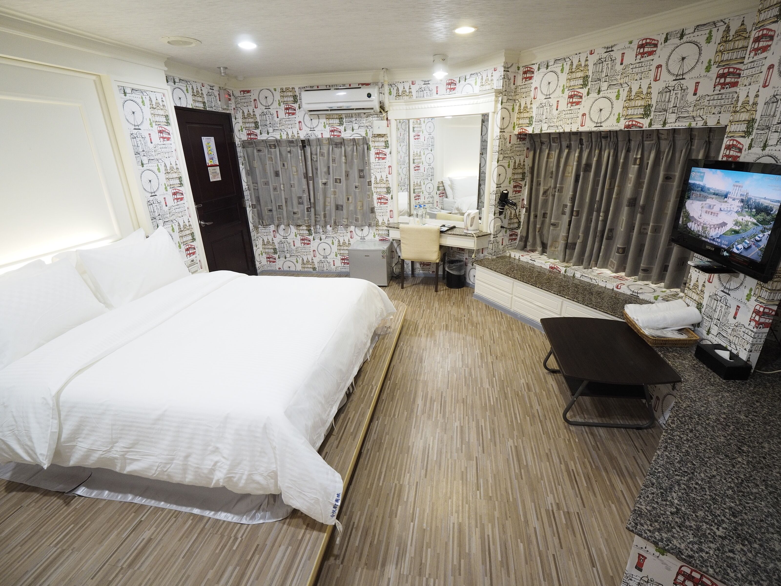 A hotel room with a bed, a desk, a chair, a TV, and a bathroom.
