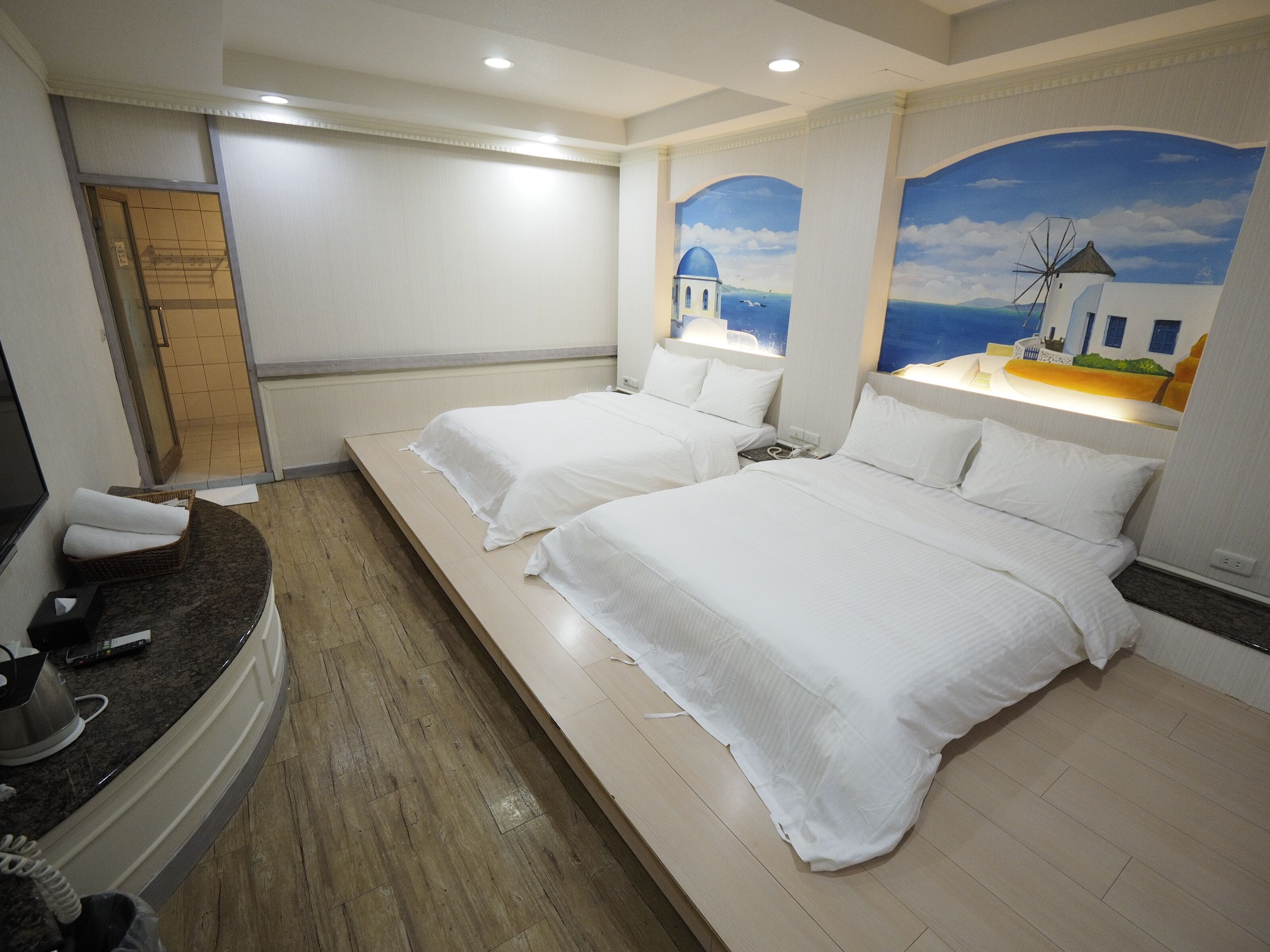 A hotel room with two beds, a TV, and a bathroom with a shower.