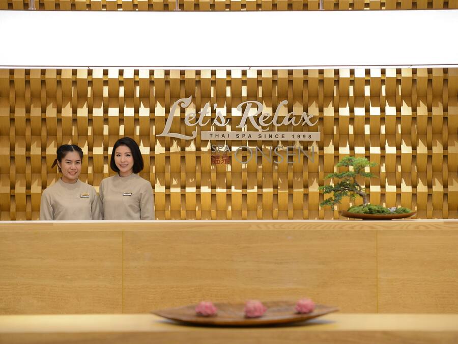Un espace d’accueil avec un mur en bois et une enseigne sur laquelle on peut lire : « Let’s Relax Thai Spa, depuis 1998. »