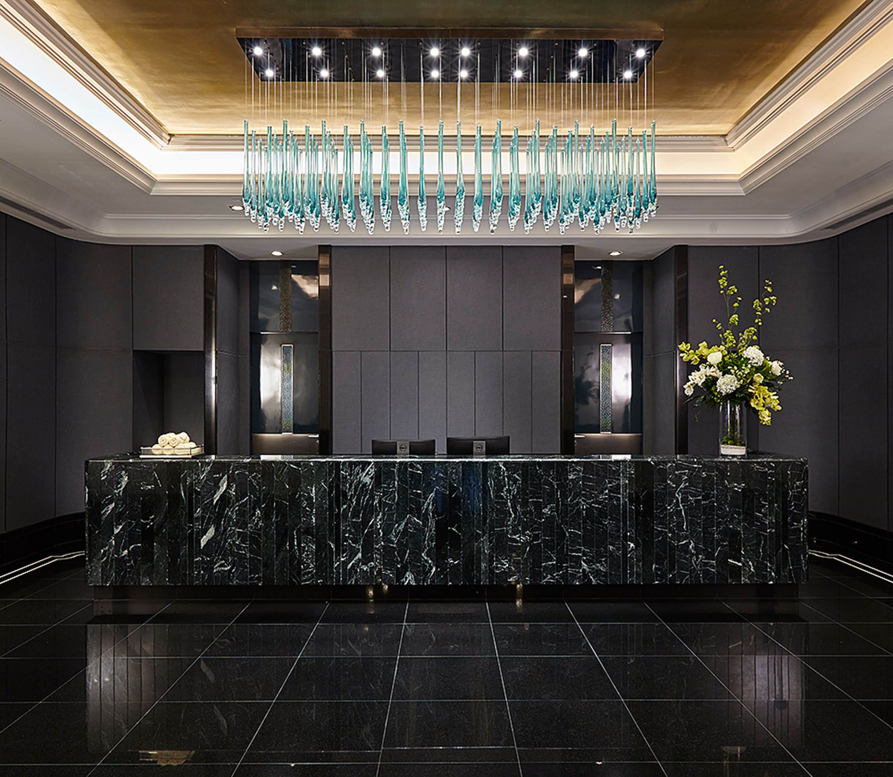 A reception area with a marble counter, a chandelier, and a vase of flowers.
