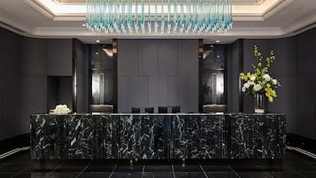 A reception area with a marble counter, a chandelier, and a vase of flowers.