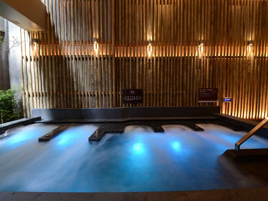 A hot spring bath with bamboo walls and a sign indicating the temperature.